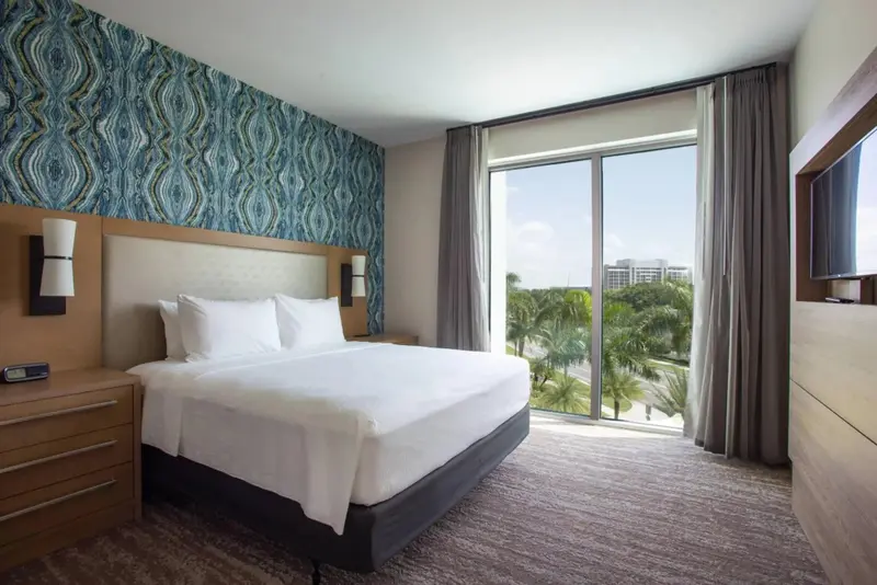 Une chambre lumineuse avec un grand lit et une vue sur la végétation.