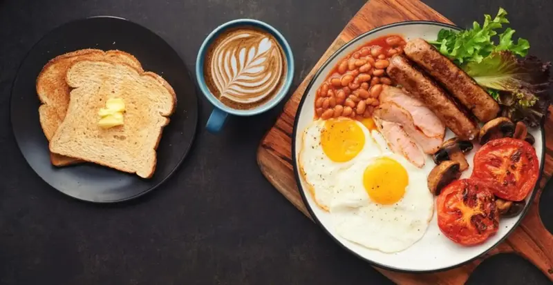 Un petit-déjeuner copieux est présenté sur une planche en bois sombre.
