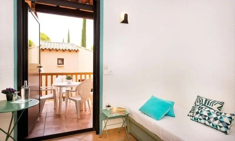 Une pièce lumineuse s'ouvre sur une terrasse avec table et chaises.