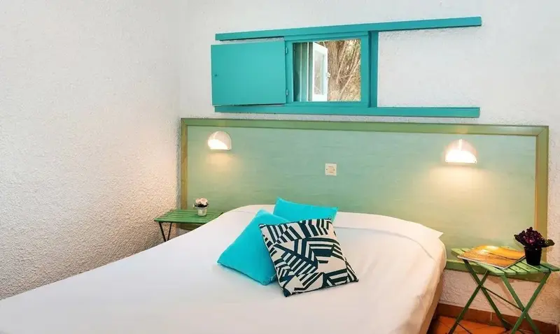 Une chambre lumineuse avec un lit simple et des meubles turquoise.