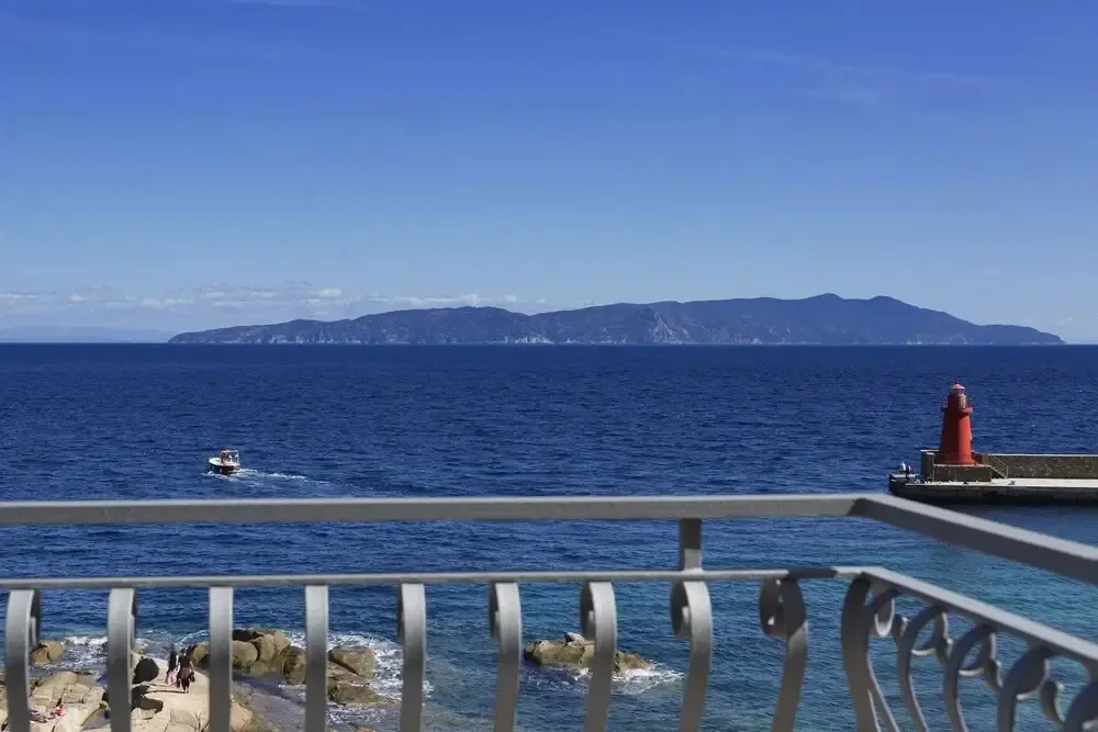 Vue sur la mer et une côte rocheuse depuis un balcon.