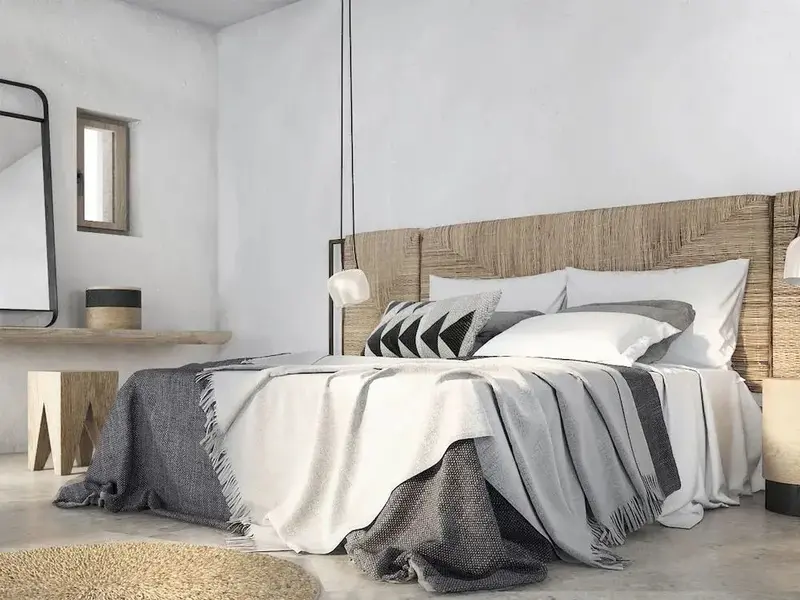 Une chambre lumineuse avec un grand lit recouvert de textiles clairs et foncés.
