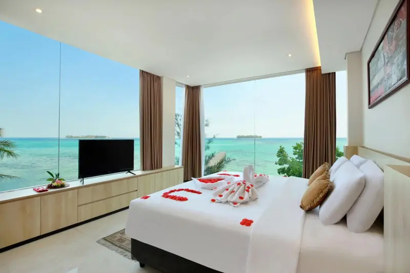 Une chambre lumineuse avec un grand lit décoré de fleurs, donnant sur une vue sur la mer.