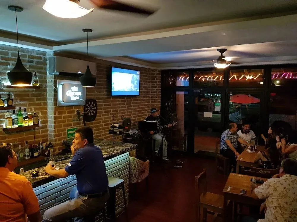 Un groupe de personnes est assis autour d'un bar et de tables dans un espace éclairé.