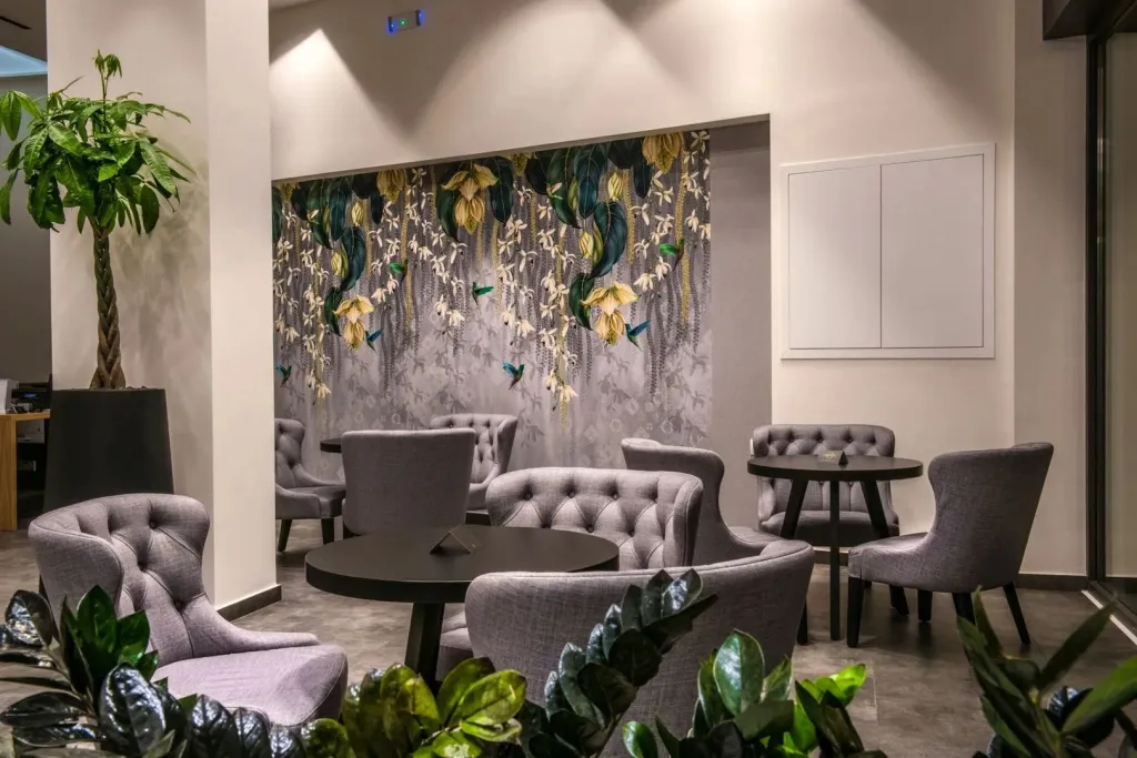 Un espace de détente avec des fauteuils et des tables basses devant un mur décoré.