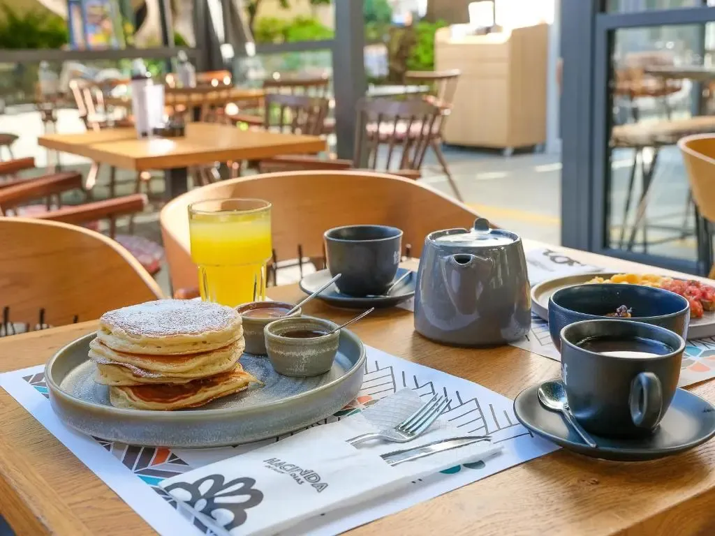 Une table est dressée avec des crêpes, des boissons et de la vaisselle.