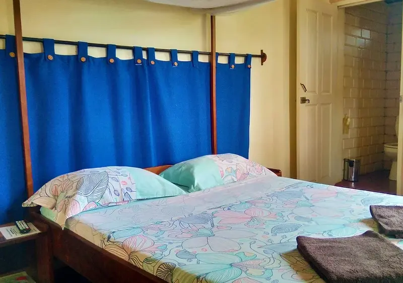 Une chambre lumineuse avec un grand lit recouvert d'une couette colorée.