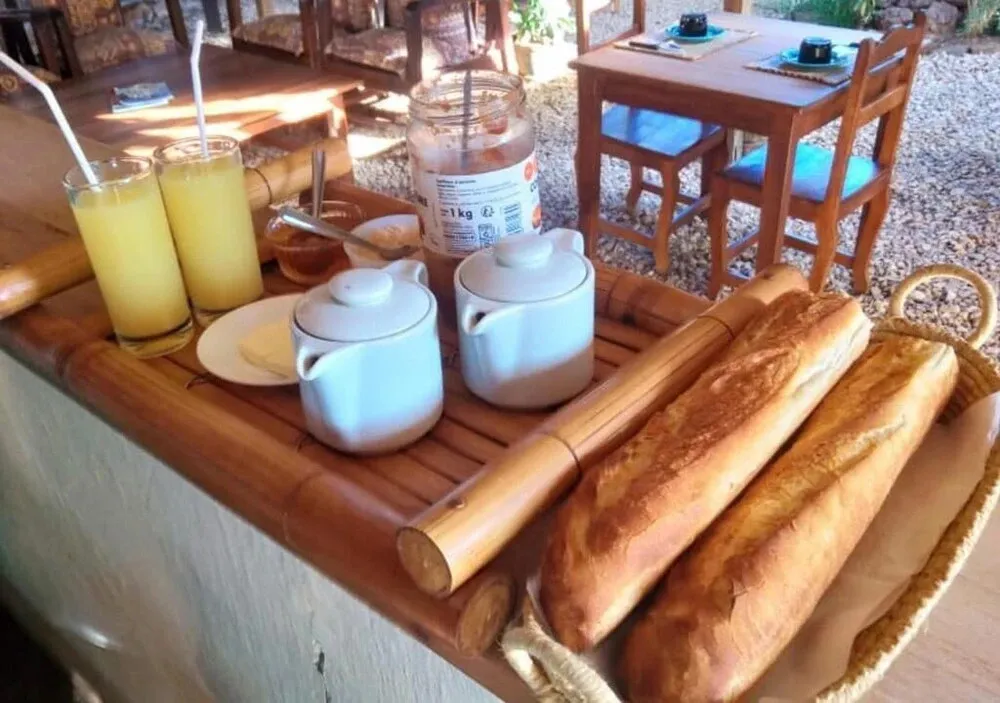 Une table en bambou présente des boissons, de la confiture et des pains frais.