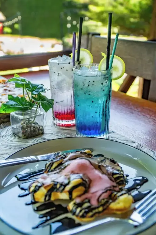 Une table en bois présente des crêpes garnies et des boissons rafraîchissantes.
