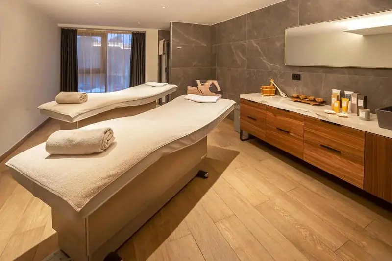 Deux tables de massage sont disposées dans une pièce lumineuse et moderne.
