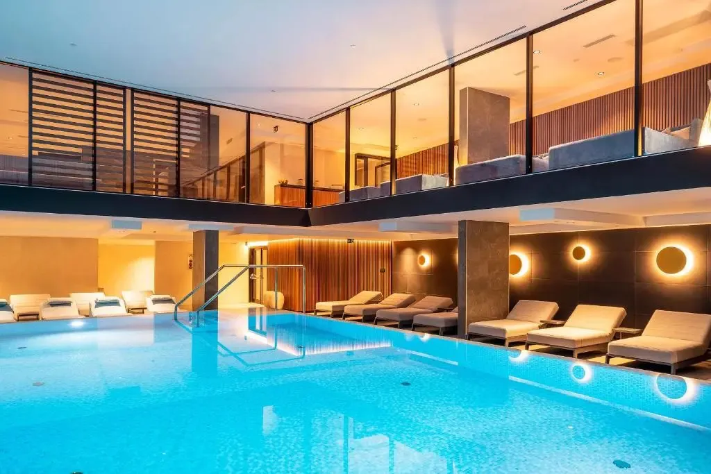 Une piscine intérieure lumineuse avec des transats alignés le long du bord.