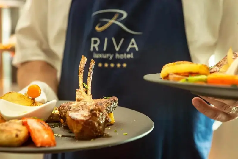 Un serveur présente des plats de viande et de légumes.