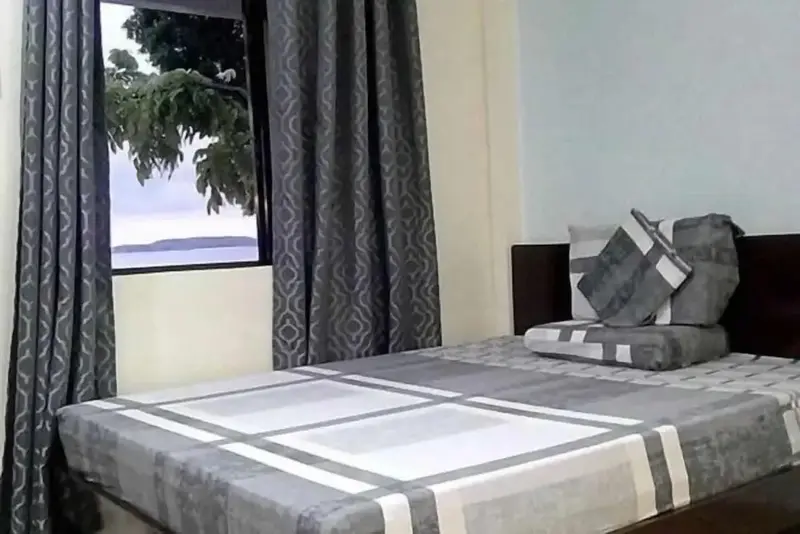 Une chambre lumineuse avec un lit et une vue sur la mer par la fenêtre.