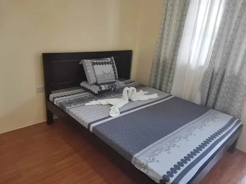 Une chambre avec un grand lit recouvert d'une couette et de coussins.
