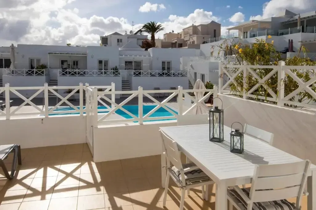 Terrasse aménagée avec table et chaises donnant sur une piscine.