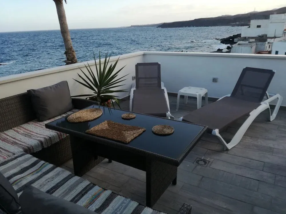 Terrasse aménagée avec salon de jardin et vue sur la mer.