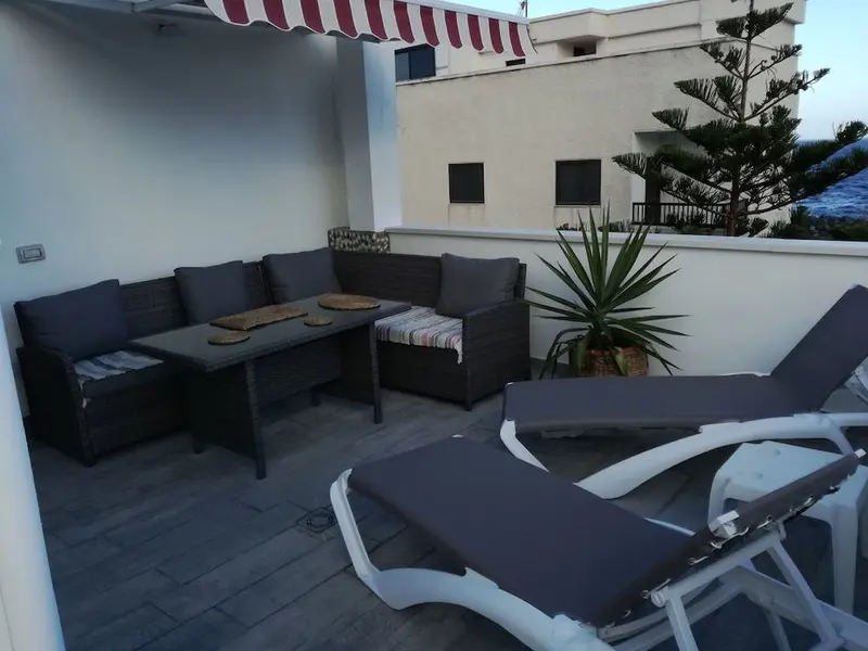 Espace extérieur aménagé avec salon de jardin et chaises longues.
