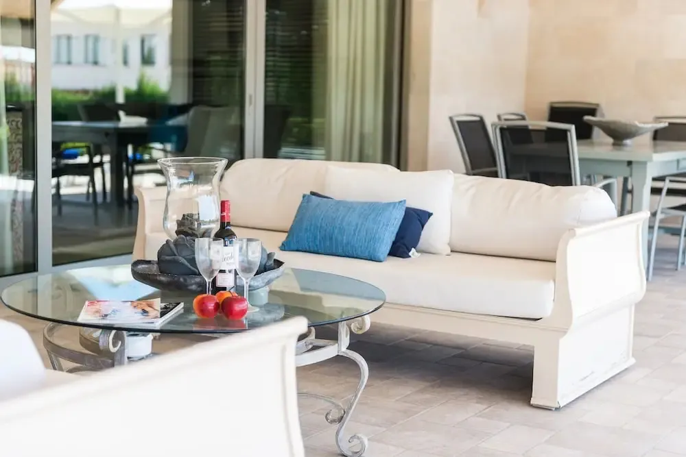 Un canapé blanc et une table basse en verre invitent à la détente sur une terrasse.