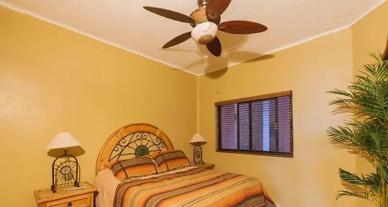 Une chambre à coucher lumineuse avec un lit recouvert d'une courtepointe colorée et une plante verte.