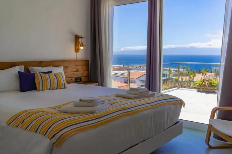 Chambre lumineuse avec un grand lit donnant sur une vue mer.