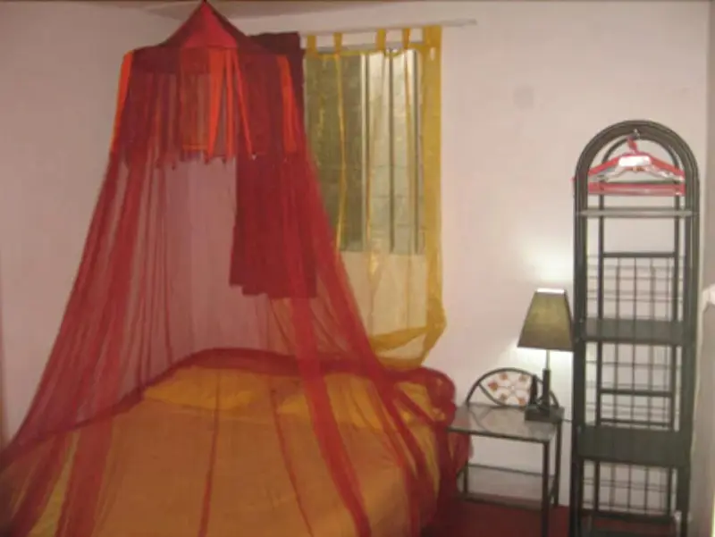 Un lit recouvert d'une moustiquaire rouge dans une chambre.