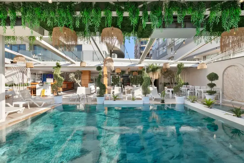 Une piscine rectangulaire bordée de chaises longues et de végétation luxuriante.