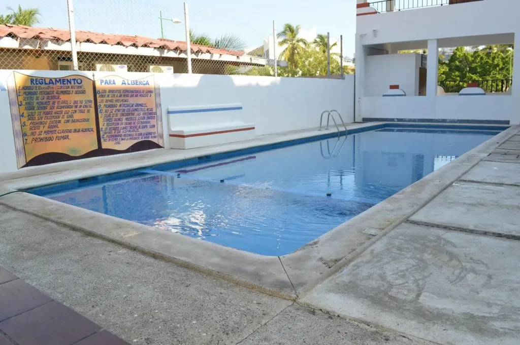 Une piscine rectangulaire entourée d'une terrasse carrelée.