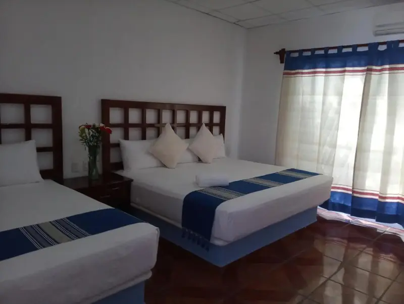 Une chambre lumineuse avec deux lits simples et des rideaux bleus.