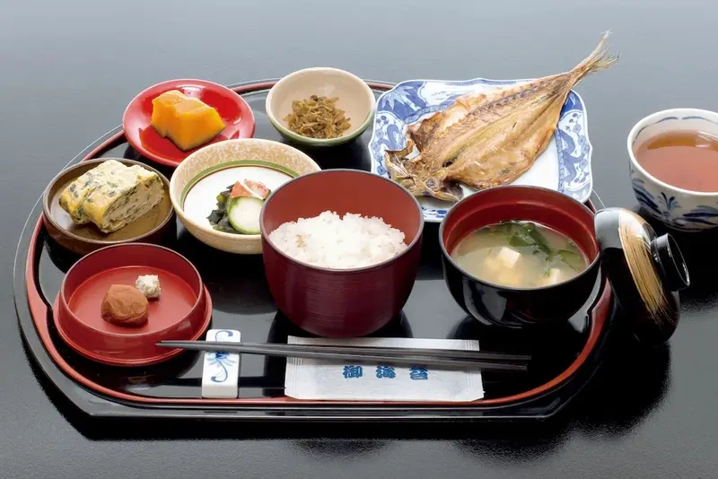 Un plateau de repas japonais avec plusieurs petits plats et une tasse de thé.