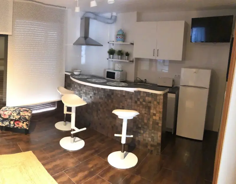 Une cuisine moderne avec un îlot central et des tabourets.