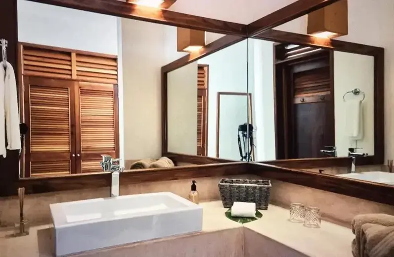 Une salle de bain lumineuse avec un grand miroir et des éléments en bois.