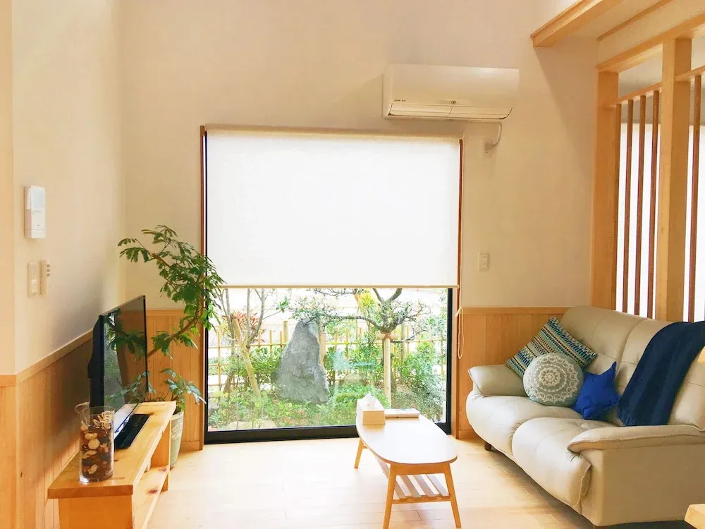 Espace de vie lumineux avec canapé et vue sur un jardin.