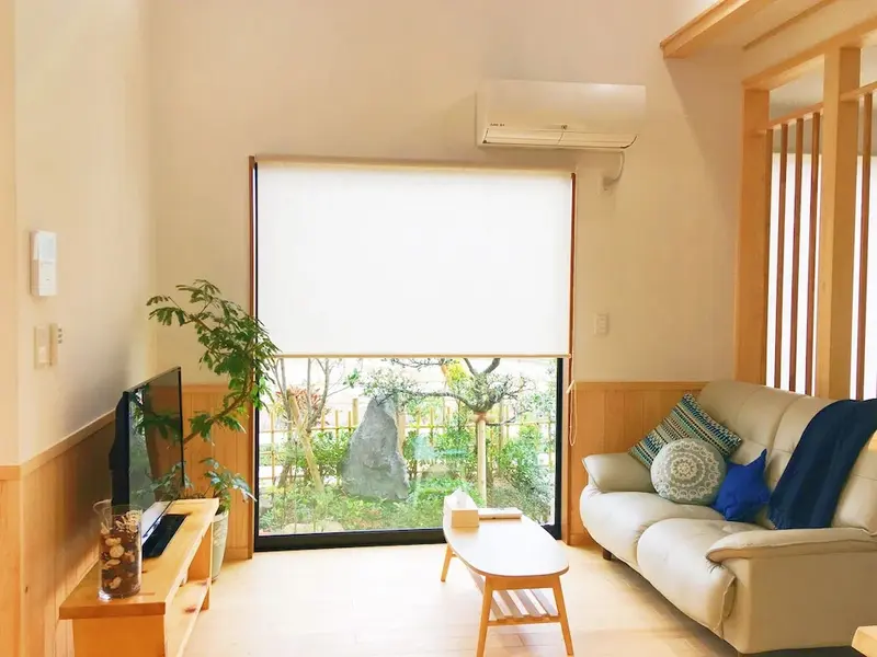 Espace de vie lumineux avec canapé et vue sur un jardin.