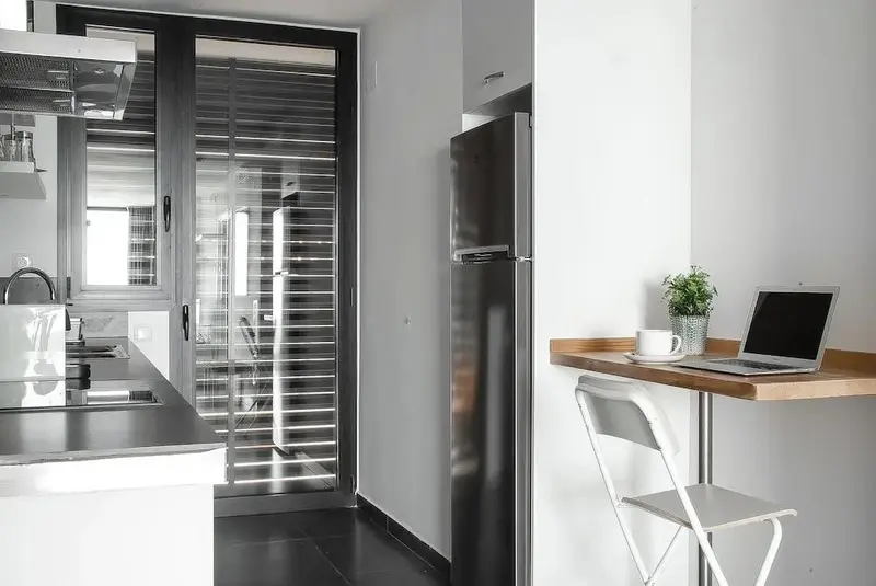 Une cuisine moderne s'ouvre sur un espace repas avec un ordinateur portable.