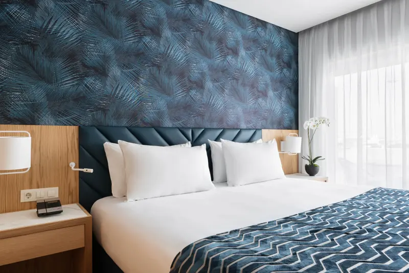 Une chambre lumineuse avec un grand lit recouvert d'une courtepointe bleue.