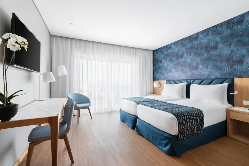 Une chambre lumineuse avec deux lits simples et un bureau.