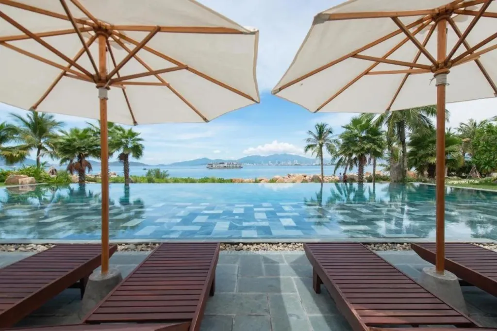 Transats et parasols bordent une piscine à débordement avec vue sur la mer.