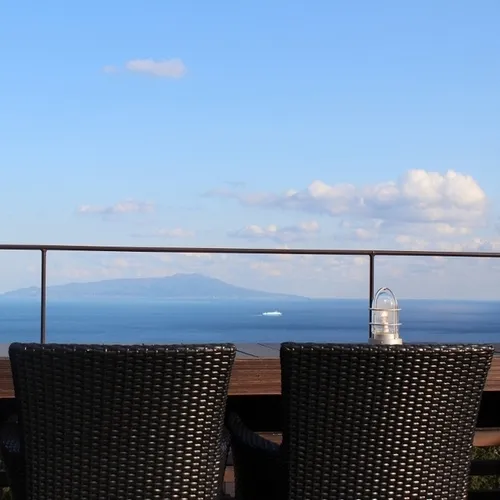 Vue sur la mer depuis une terrasse avec une table et des chaises.
