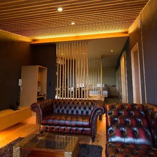 Un salon chaleureux avec des fauteuils en cuir et un éclairage tamisé.