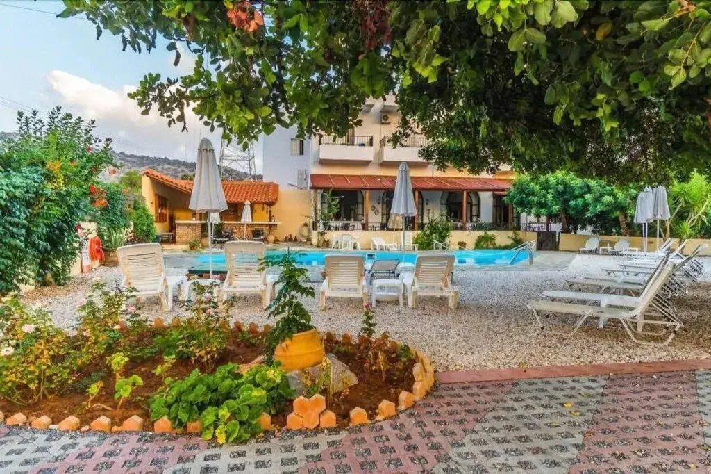 Transats et parasols bordent une piscine dans un jardin fleuri.