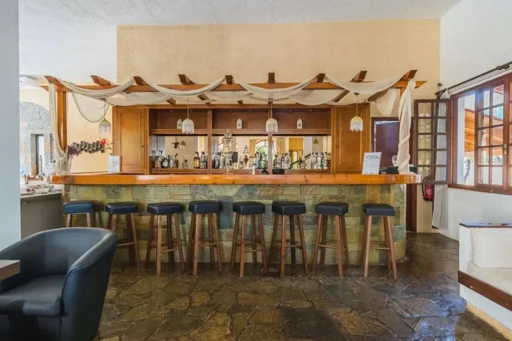 Un comptoir de bar en bois avec des tabourets est présenté dans une pièce lumineuse.