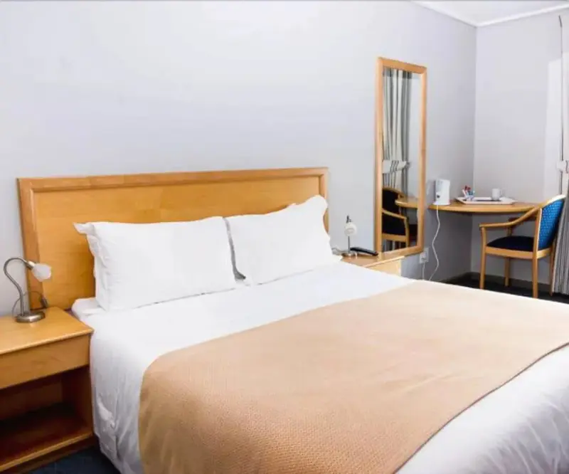 Une chambre lumineuse avec un lit double et un bureau.