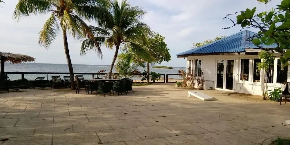 Terrasse pavée avec mobilier de jardin face à la mer.