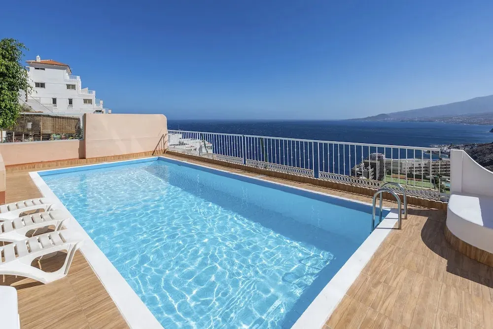 Une piscine rectangulaire avec des transats en bord de mer.