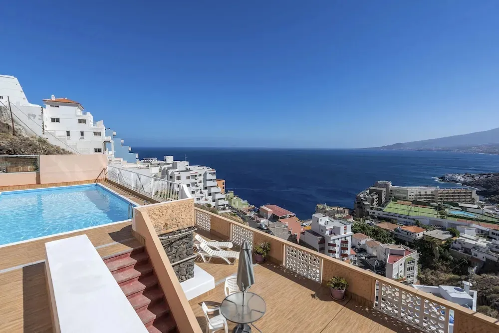 Terrasse avec piscine et vue sur la mer et les bâtiments environnants.