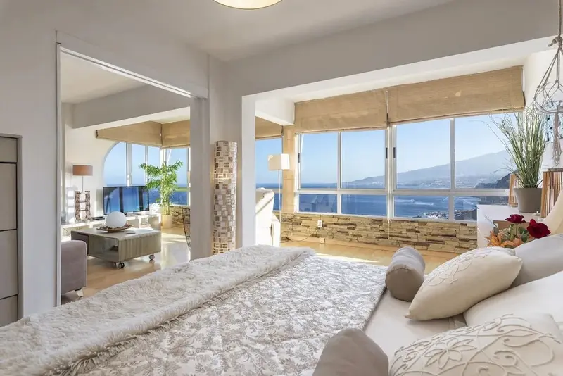 Une chambre lumineuse avec un grand lit donnant sur une vue mer.