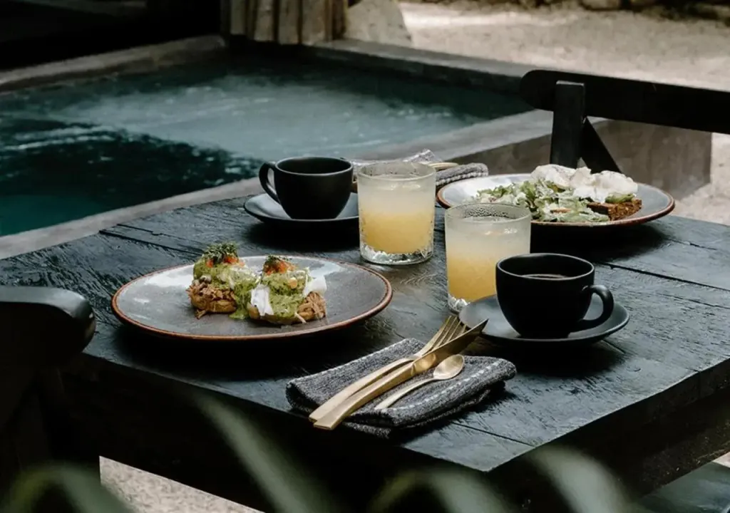 Une table en bois sombre est dressée avec des plats et des boissons.