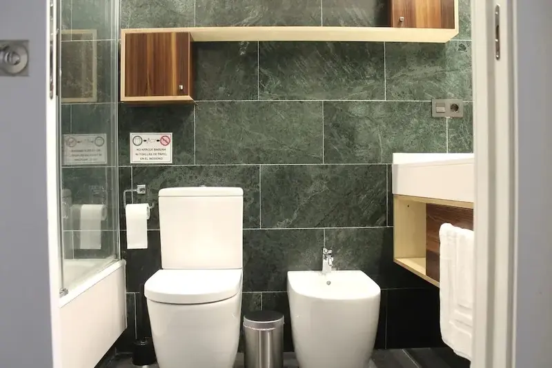 Une salle de bain moderne avec des carreaux verts et des sanitaires blancs.