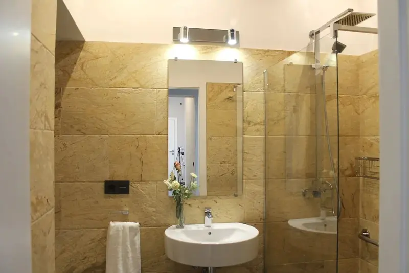 Une salle de bain lumineuse avec des murs carrelés et une douche vitrée.