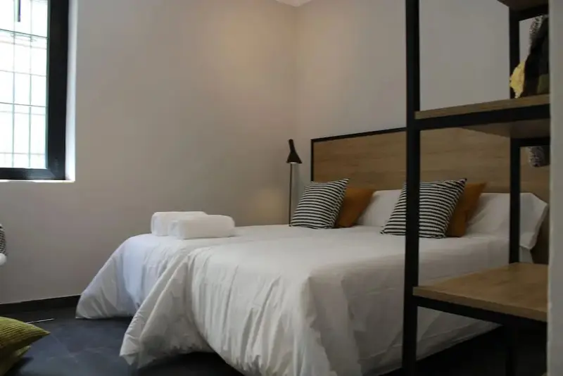 Une chambre lumineuse avec un grand lit recouvert de draps blancs et de coussins.